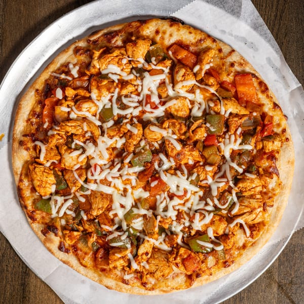 Turkish chicken pizza with melted cheese, green peppers, and red peppers on a metal tray.