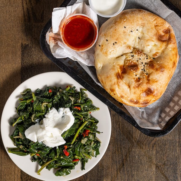 Turkish flatbread with sesame seeds, a side of sauteed spinach with yogurt, and dipping sauces.