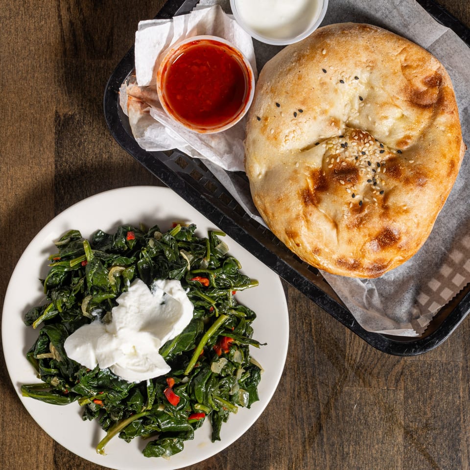 Turkish flatbread with sesame seeds, a side of sauteed spinach with yogurt, and dipping sauces.
