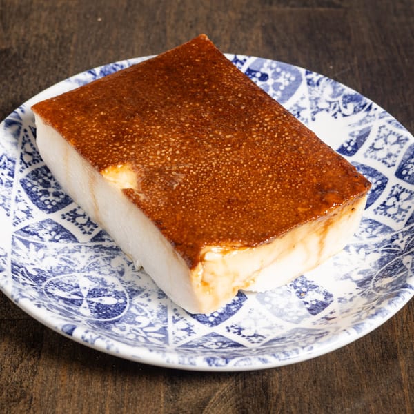 A rectangular slice of Turkish kazandibi, a milk pudding with a caramelized top, on a blue and white plate.